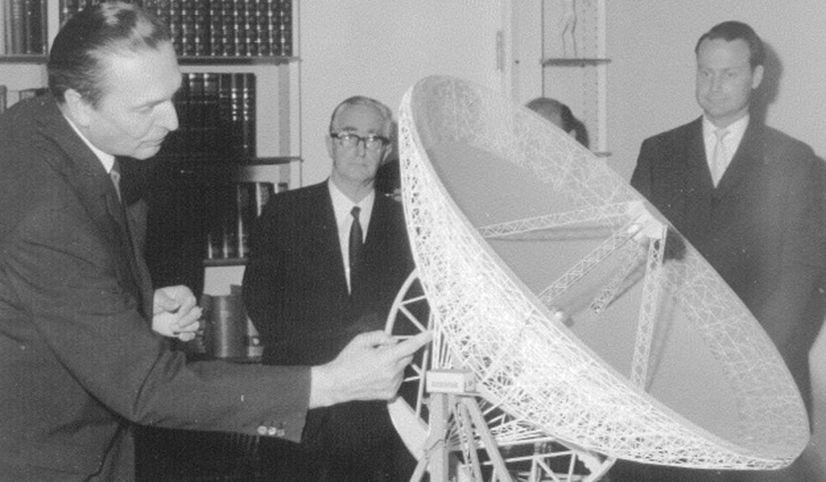 Men stand around a model of a radio telescope