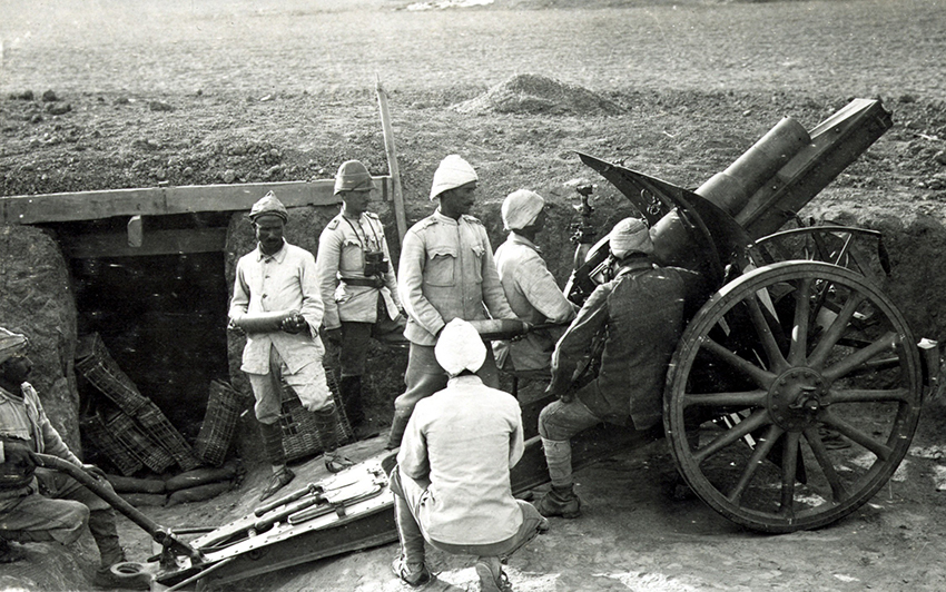 Historische Aufnahme von Männern, die an einer Kanone stehen, welche sich in einem Schützengraben befindet.