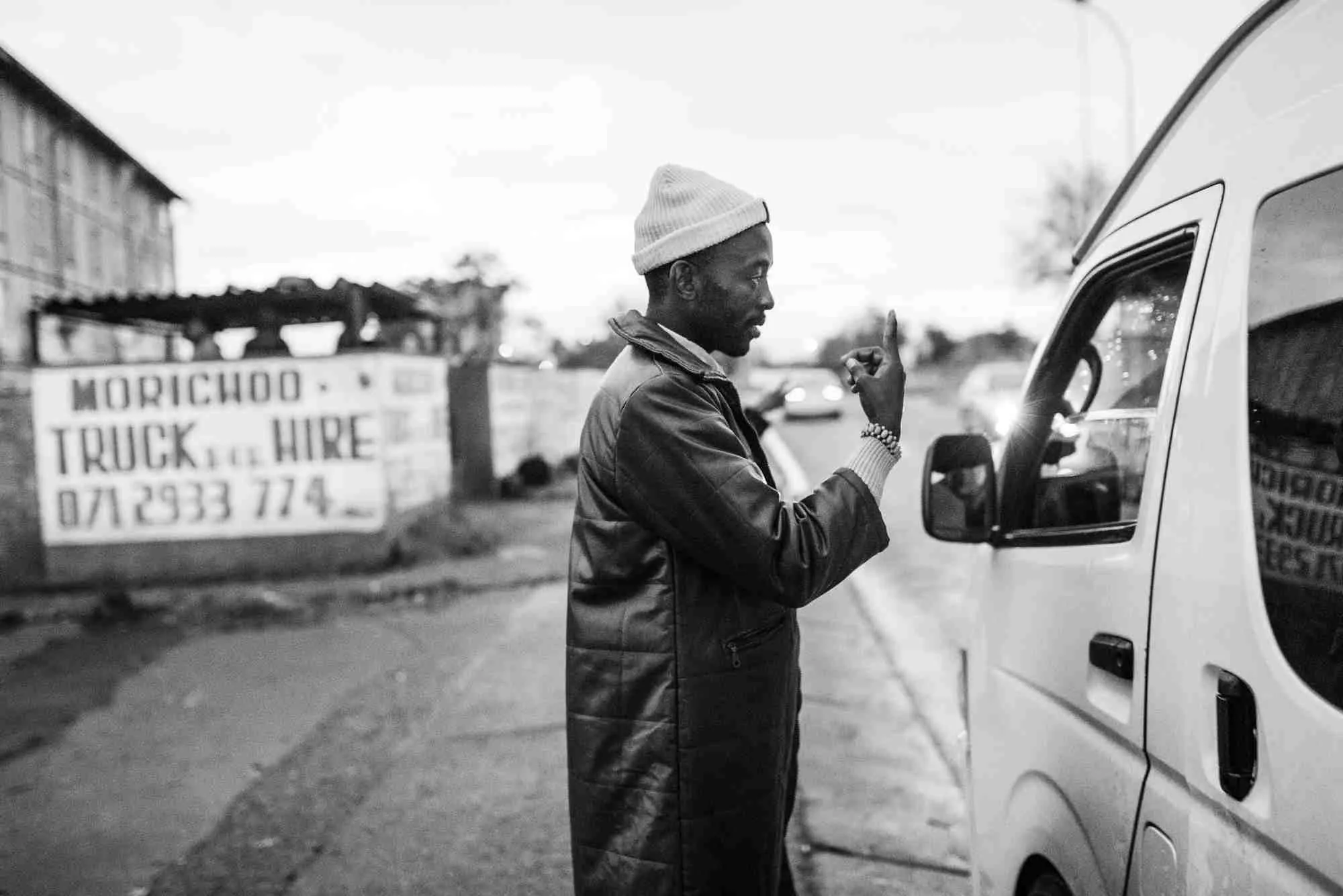 Ein Mann in Johannesburg (Südafrika) zeigt einem Kleinbus per Handzeichen, in welche Richtung er fahren möchte.