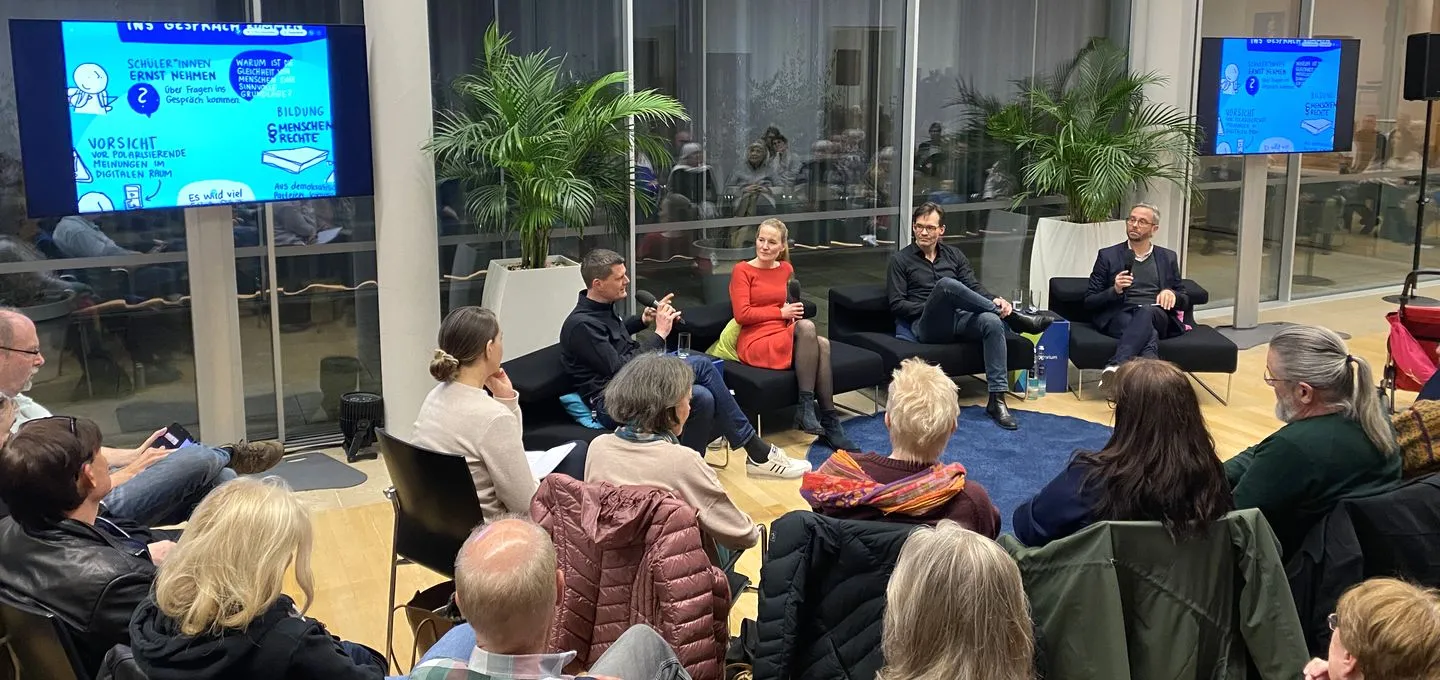 vier Menschen diskutieren vor Publikum