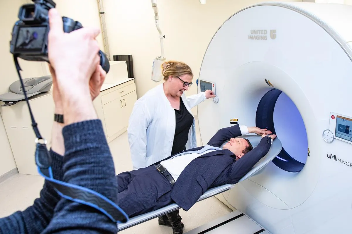 Ein Mann legt sich mit den Armen über den Kopf auf die fahrbare Untersuchungsliege des Medizingeräts.