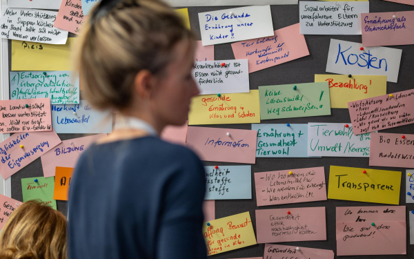 Frau steht vor einer Wand voll bunter Karteikarten mit notierten Gedanken