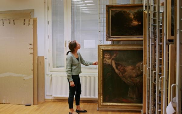 Frau in einem Museumsarchiv mit großformatigen Gemälden