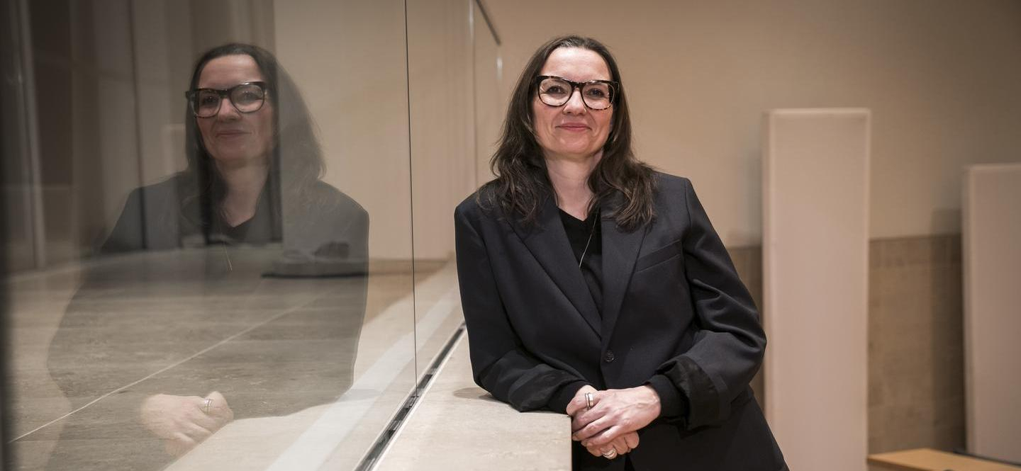 Eine Frau lehnt an einer Brüstung und schaut in die Kamera