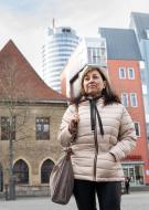 Frau auf einem Platz, im Hintergrund Gebäude