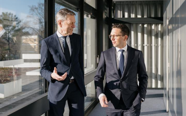 Zwei Männer laufen diskutierend einen Flur entlang