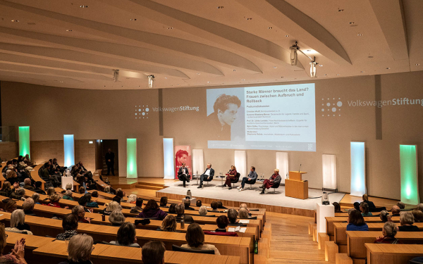 Podium mit Gästen im gut besuchten Auditorium