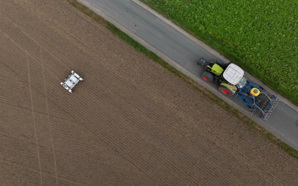 Feld aus der Vogelperspektive mit einem Roboter und Traktor