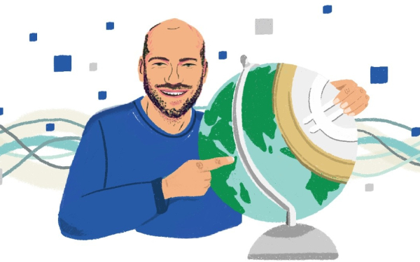 Ein Mann hält einen Globus im Arm und zeigt darauf.