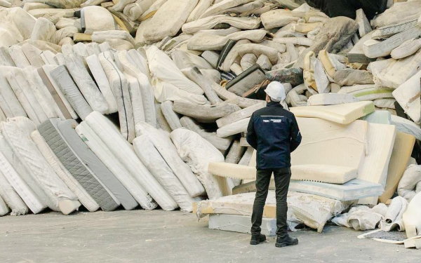 Ein Mann steht vor einem großen Berg alter Matratzen