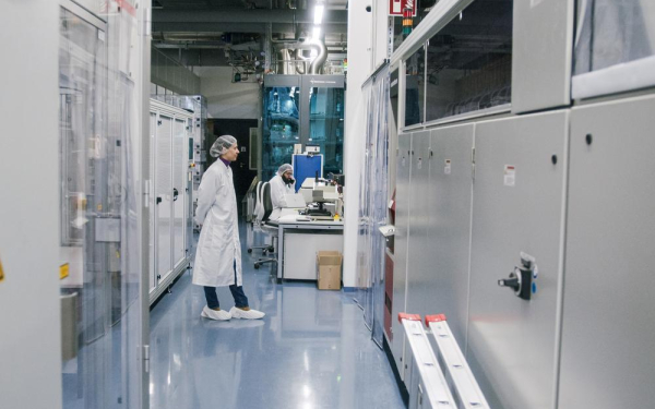 Woman stands in a modern industrial hall and observes a machine