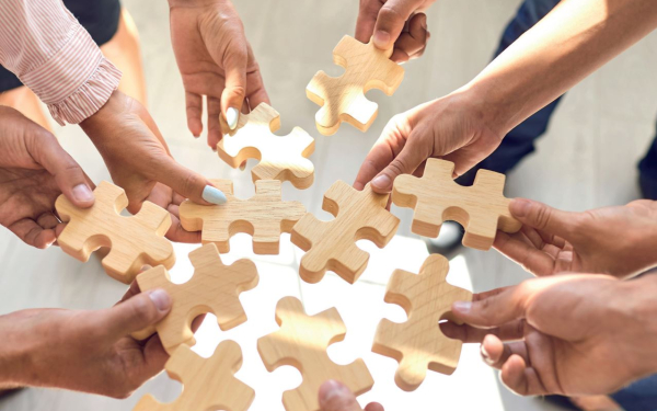 viele Hände mit Holzpuzzlesteinen