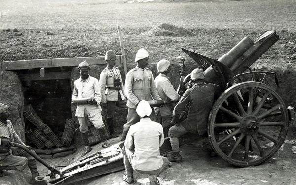 Historical photograph of men standing by a cannon located in a trench.