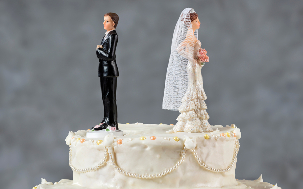 Zu sehen ist eine Hochzeitstoprte mit Dekofiguren Braut und Bräutigam, die sich den Rücken zuwenden. 