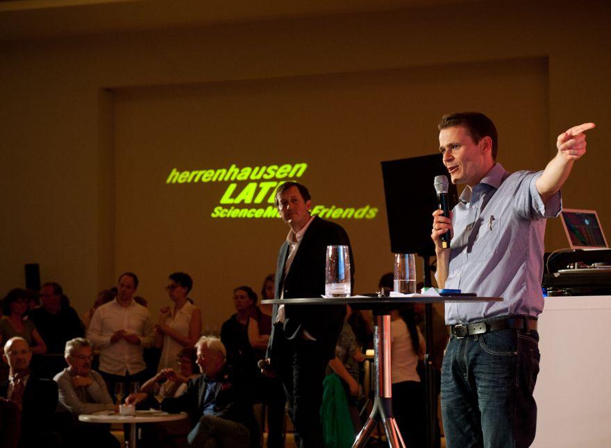Ein Mann auf dem Podium, im Hintergrund der Schriftzug "Herrenhausen Late"