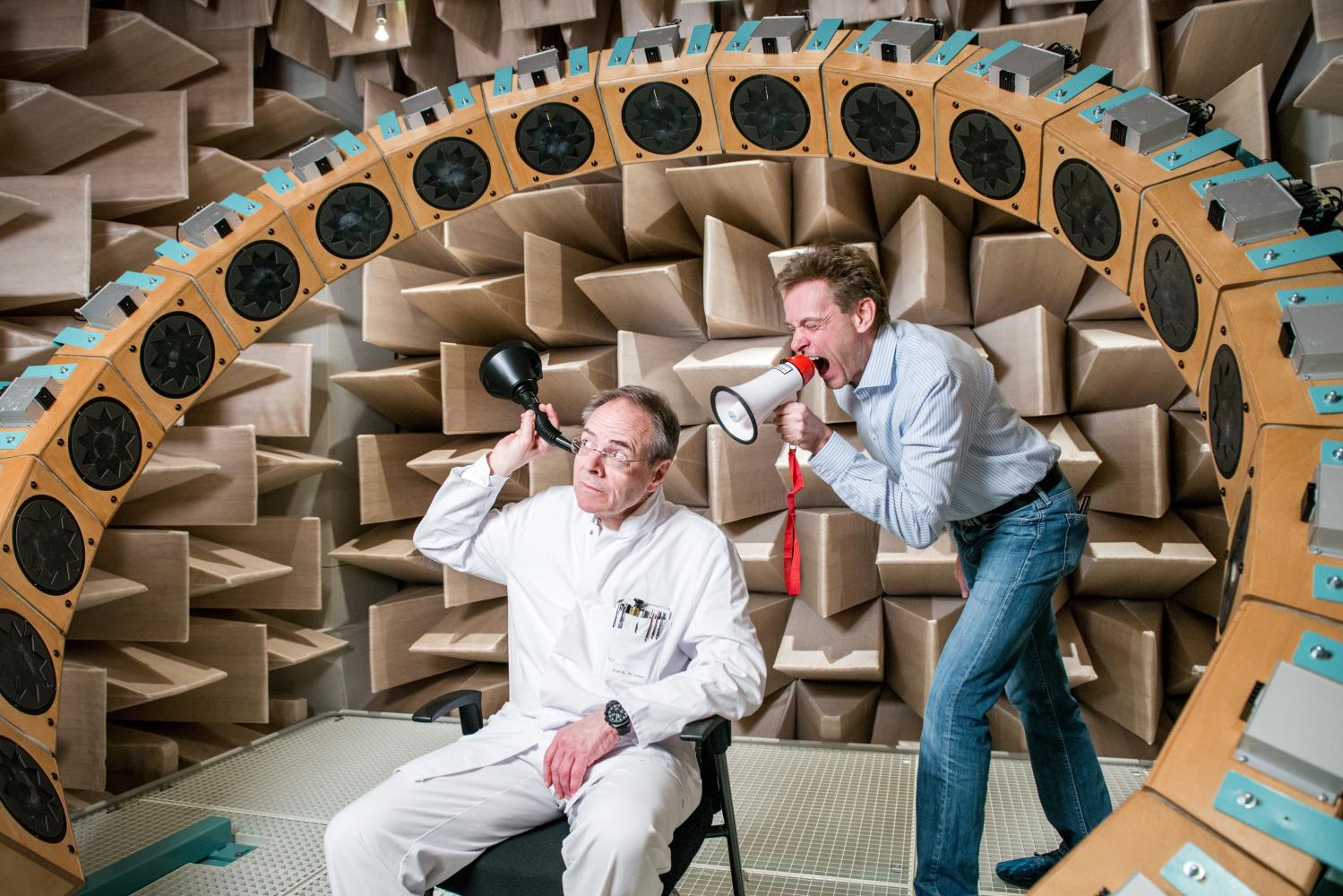 ein Mann mit Hörrohr, dahinter ein Mann mit Megafon