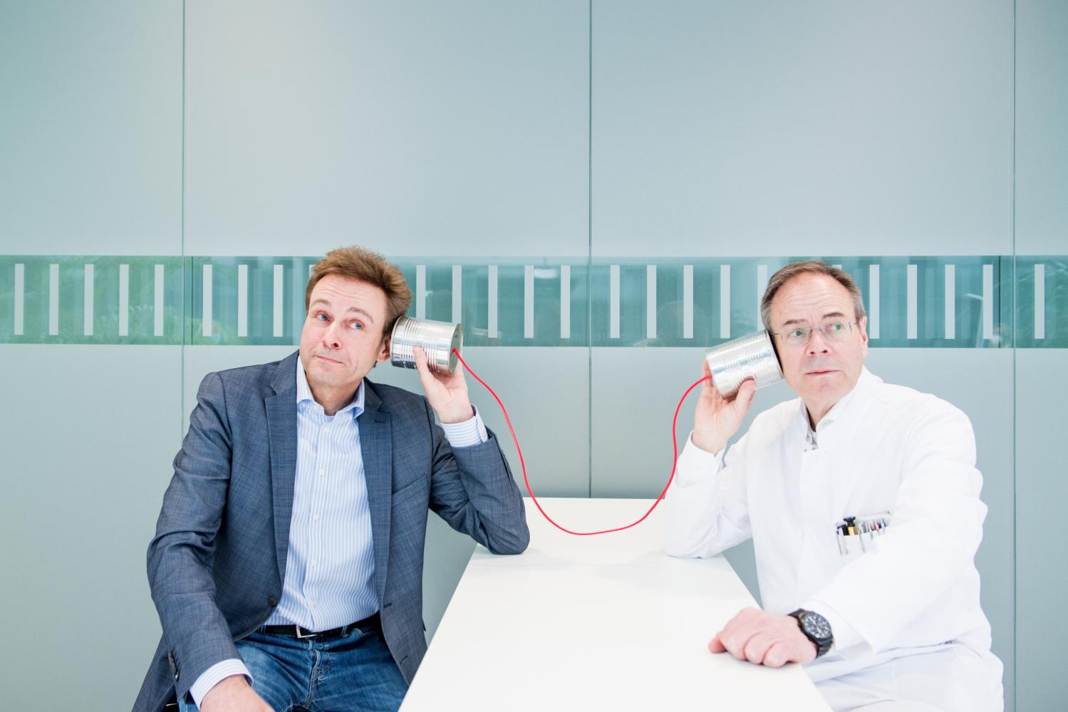 zwei Personen lauschen in ein Schnurtelefon