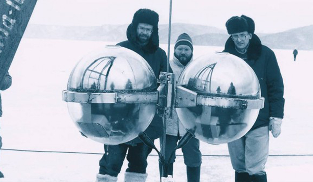 Drei Männer im Schnee vor einer mechanischen Apparatur.