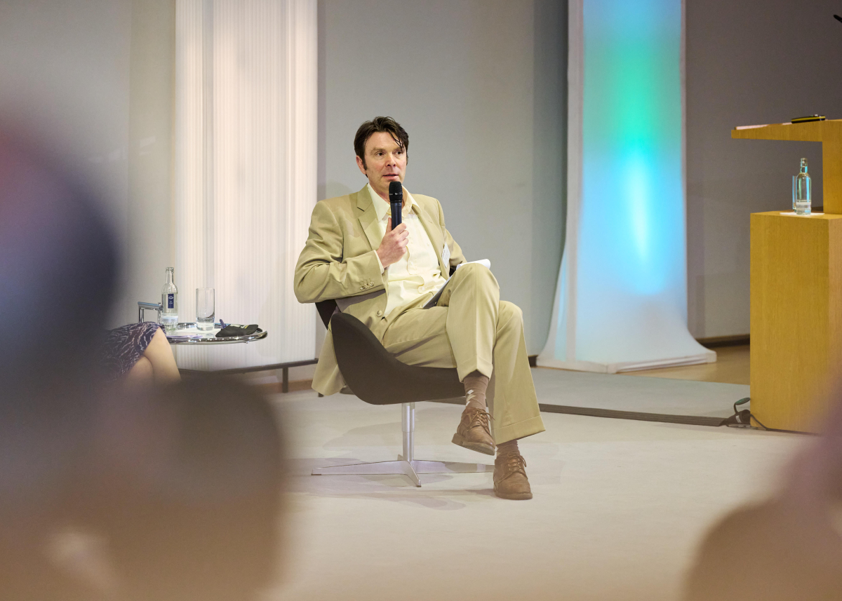 Jörg Tremmel sitzt auf einem Podium