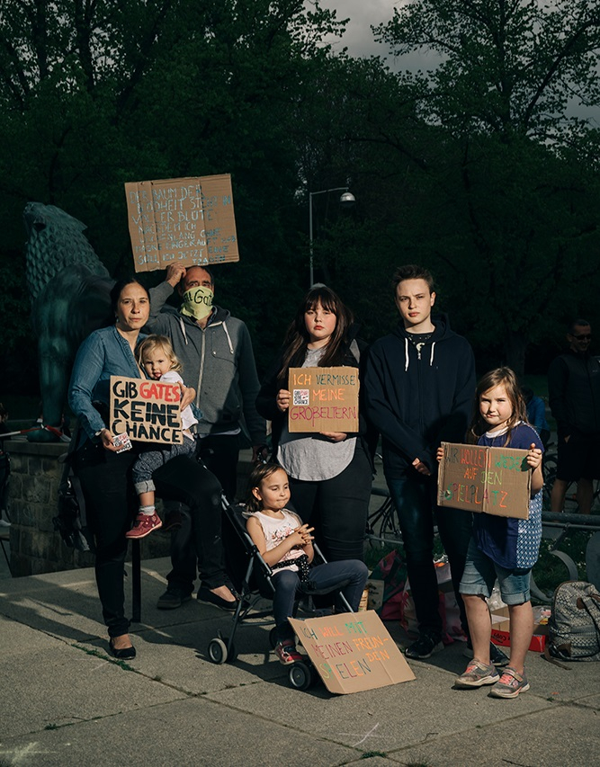 Eine Gruppe von Erwachsenen und Kindern protestieren mit Plakaten gegen die Corona-Maßnahmen.