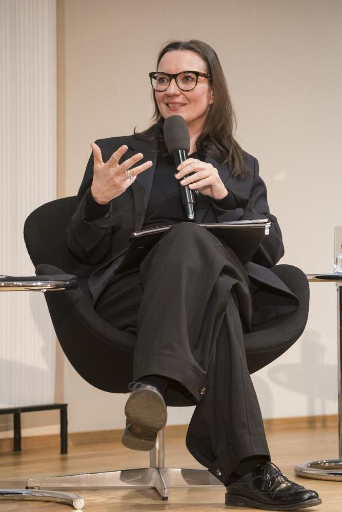Eine Frau hält ein Mikrophon in der Hand und gestikuliert.