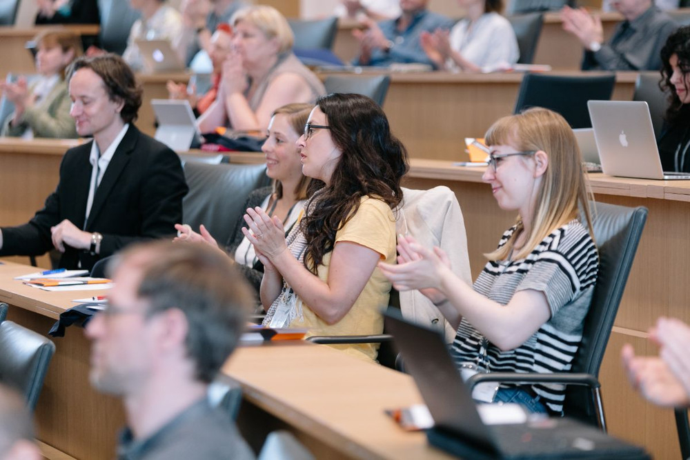 Menschen applaudieren. Sie sitzen in einem Auditorium.