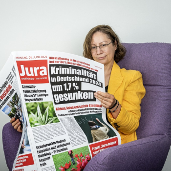 Das Bild zeigt die Referentin Prof. Dr. Susanne Beck mit einer Zeitung lesend und im Seesel sitzend.