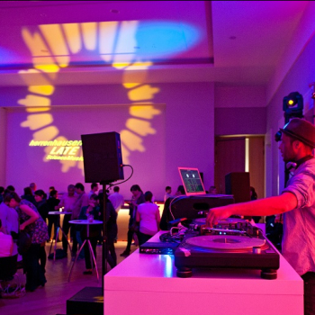 Das Bild zeigt eine Szene mit DJ und Publikum in loungiger Atmosphäre