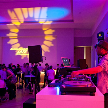 Das Bild zeigt ein Szene DJ und Publikum in loungiger Atmosphäre