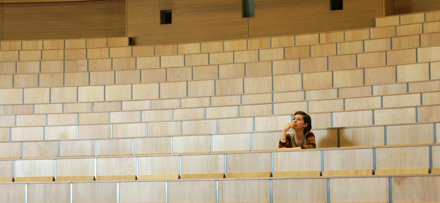 Frau sitzt allein in einem Hörsaal