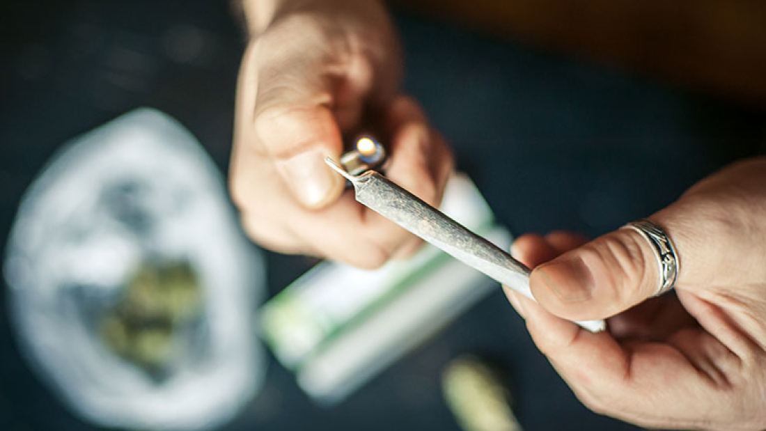 Zu sehen sind die Hände eines Menschen, der einen Joint anzündet.