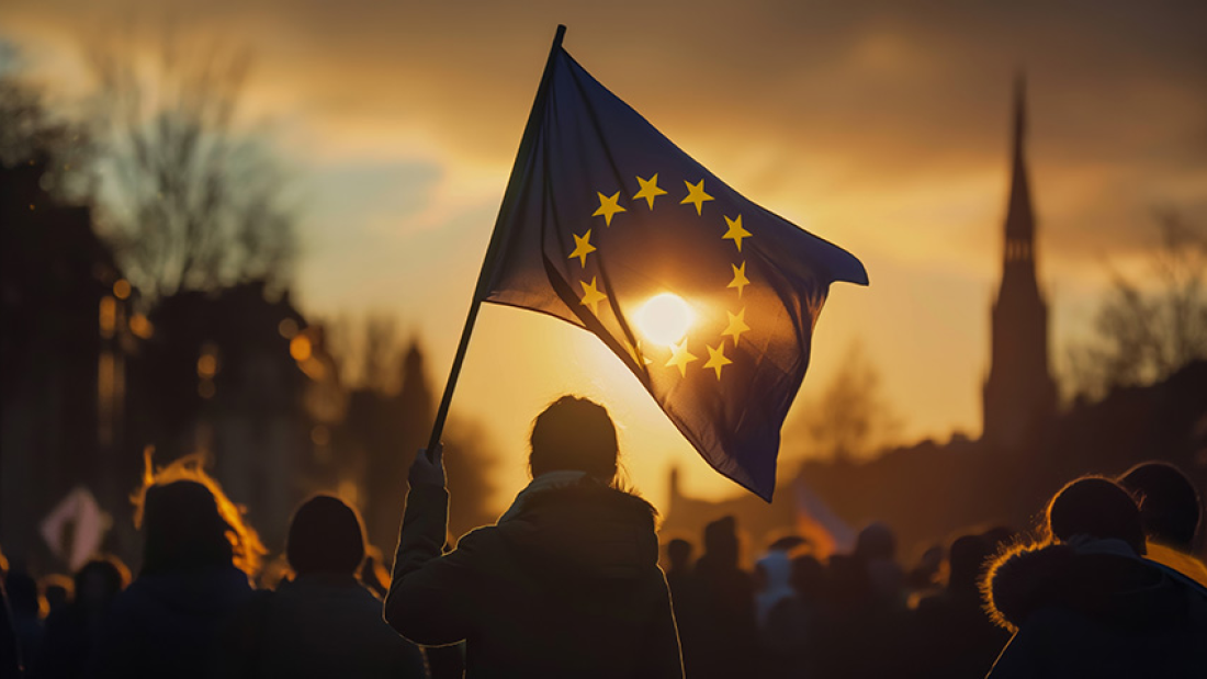 Das Bild zeigt eine EU-Flagge vor der untergehenden Sonne.