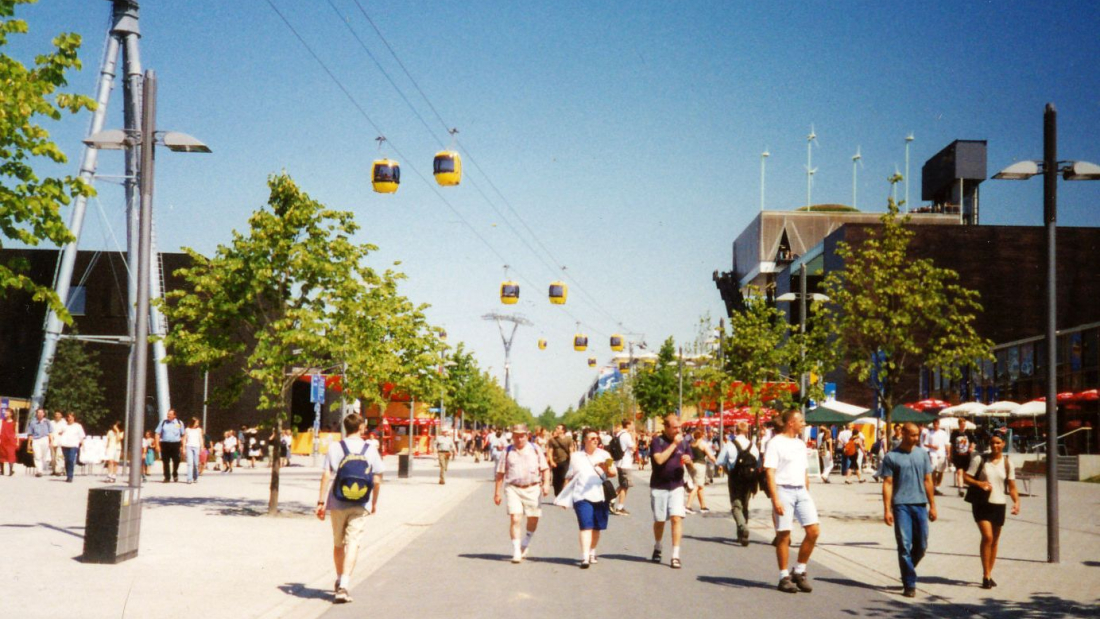 Menschen flanieren unterhalb einer Seilbahn